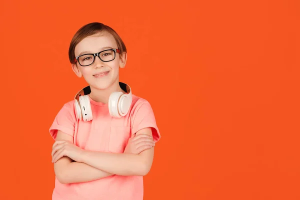 오렌지 배경에 헤드폰을 귀여운 소년의 안경을 아이가 생각을 합니다 — 스톡 사진
