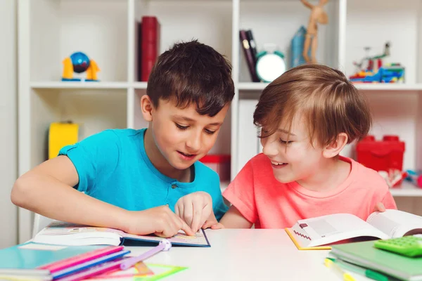 Happy school kids at lesson in classroom. Education and development. Back to school concept. Cute industrious children are sitting at the desk. Kids are learning in class.