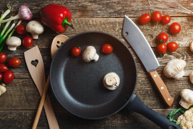 Ahşap arka planda mutfak aletleri ve baharatlar, üst manzara. Koyu ahşap masada yemek arkaplanı. Siyah tavayla yemek pişirmek için gerekli malzemeler. Yemek pişirmek için çeşitli ürünler.