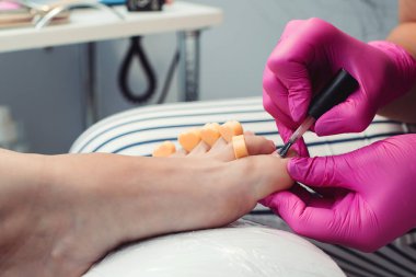 Kuaförde pedikür yaptıran bir kadın. Pedikür ve ayak bakımı. Kadın kuaförde dinleniyor, tırnakları umursuyor. Güzellik salonunda profesyonel pedikür. Ayak tedavisi. Bacaklar için güzellik tedavisi.