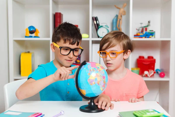 Okul çocukları dünyayı inceliyor. Eğitim ve coğrafya. Okula dönelim. Gülümseyen öğrenciler küreye bakıyor. Coğrafya okuyan zeki çocuklar. Çocuklar birlikte ödev yapıyorlar..