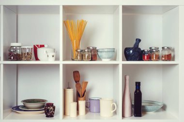 Mutfak gereçleri ve sofra takımı beyaz raflarda. İyi organize edilmiş mutfak konsepti. Modern iç mekan. Temiz bulaşıklarla dolu dolabı aç. Mutfakta rafları açın..
