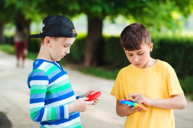 Yakışıklı çocuklar modaya uygun oyuncaklarla oynuyorlar. Silikon balonlu oyuncaklarla gezen arkadaşlar. Çocuklar dışarıda eğleniyor. Çocuklar için modern anti-stres oyuncağı. Moda, yaşam tarzı ve çocuklar için eğlence.