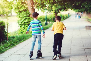 Çocuklar sokakta scooter 'a binip paten kayıyorlar. Arkadaşların dışarıda birlikte vakit geçirmesi. Çocuklar için açık hava sporu. Arkadaşlık, eğlence ve yaşam tarzı konsepti.