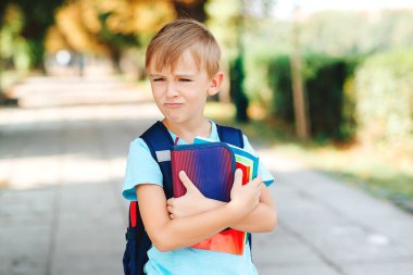 Olumsuz duyguları olan küçük bir öğrenci okula gidiyor. Eğitim, okul konseptine geri dönelim. Ellerinde kitap ve sokakta sırt çantası olan mutsuz bir okul çocuğu..