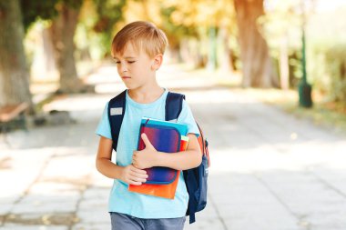 Olumsuz duyguları olan küçük bir öğrenci okula gidiyor. Eğitim, okul konseptine geri dönelim. Ellerinde kitap ve sokakta sırt çantası olan mutsuz bir okul çocuğu..