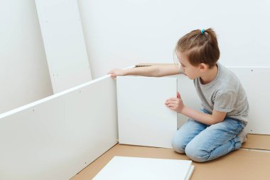 Çocuk kendisi bir kitaplık kuruyor. Baba ve küçük oğlu evde mobilya montajı yapıyor.