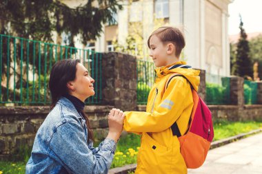 Anne çocuğuna okula kadar eşlik eder. Anne ve öğrenci birinci sınıfta okul çantasıyla el ele tutuşuyorlar. Okul konseptine geri dönelim. Annem ilkokulda küçük bir çocuğu yönetiyor..