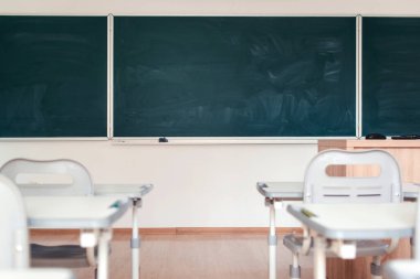 Boş okul sınıfı. Duvardaki yeşil karatahta. Eğitim konsepti. Sınıftaki tahtalar, masalar ve sandalyeler. Öğrencileri ve öğretmeni olmayan ilkokul sınıfı. Okula geri dön..
