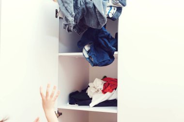 Kirli çamaşırları dolaba atan genç bir çocuk. Gardırop ve soyunma odasında karışıklık. Düzensiz düzensiz kıyafet dolabı. Dağınık çocuk odası..