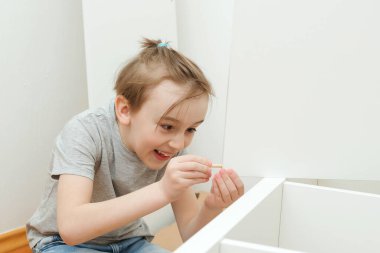 Şirin çocuk kitaplığı kendisi monte ediyor. Oğlu evde yeni mobilya montajı için babasına yardım ediyor. Mobilyaları kendin monte et. Çocukluk, yaşam tarzı konsepti.