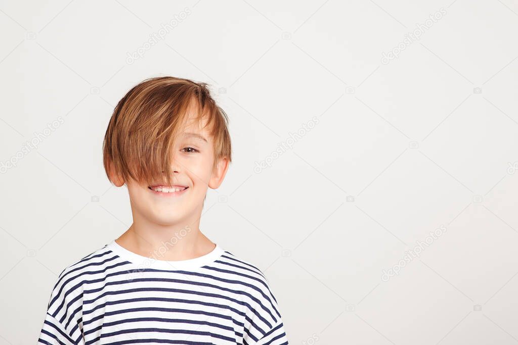 Portrait of handsome boy. Smiling boy posing at studio. Children style and fashion. Happy boy with stylish hairstyle. Happy childhood and positive emotions.