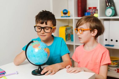 Dünya 'ya bakan zeki öğrenciler. Coğrafya okuyan çocuklar. Çocuklar birlikte ödev yapıyor. Küre üzerinde çalışan bir sınıf arkadaşım. Eğitim ve coğrafya. Okula geri dön..