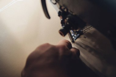 Deri işçiliğinin çalışma süreci. Tanner özel bir dikiş makinesine deri dikiyor, yakın çekim. İşçi dikiş makinesine deri ürün dikiyor. Deri işçisi atölyesi.