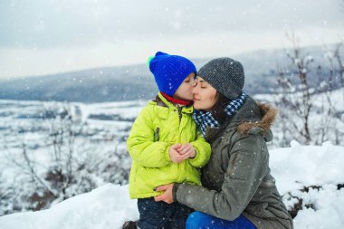 Anne ve çocuk Noel tatili boyunca birlikte eğleniyorlar. Mutlu bir aile ve çocukluk. Anne ve çocuğu karlı kış yürüyüşünde. Aile güzel kış doğasının tadını çıkarıyor. Karlı kış mevsimi.