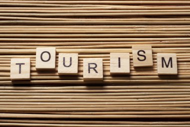 Ahşap arka planda ahşap blok üzerine yazılmış turizm kelimesi