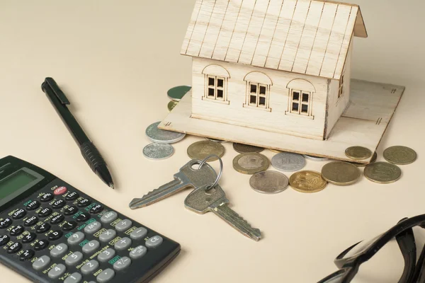 Ahorro en el hogar, concepto de presupuesto. Casa modelo, bloc de notas, pluma, calculadora y monedas en mesa de escritorio de oficina de madera . — Foto de Stock