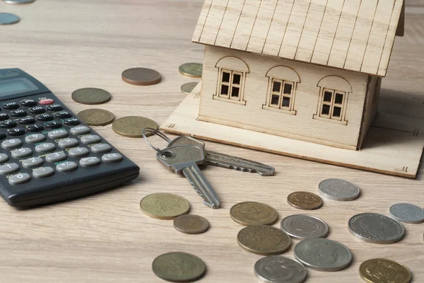 Ahorro en el hogar, concepto de presupuesto. Casa modelo, bloc de notas, pluma, calculadora y monedas en mesa de escritorio de oficina de madera . — Foto de Stock