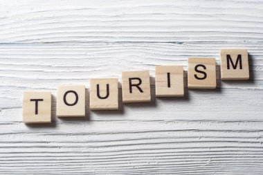 Ahşap arka planda ahşap blok üzerine yazılmış turizm kelimesi
