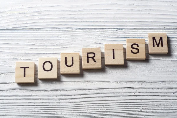 Ahşap arka planda ahşap blok üzerine yazılmış turizm kelimesi
