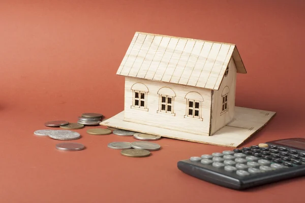 Binnenlandse besparingen, begroting concept. Model huis, Kladblok, pen, rekenmachine en munten op houten kantoor bureau tafel. — Stockfoto