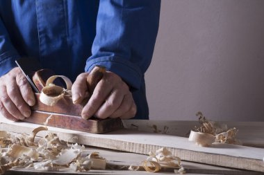 Marangoz uçak ile şantiye, ahşap arka plan üzerinde çalışıyor. Marangoz işyeri