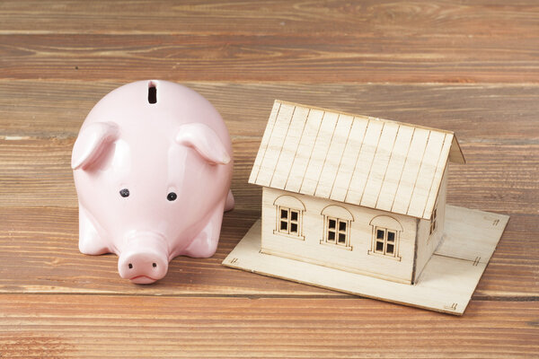 Домашние сбережения, бюджетная концепция. Модельный дом, блокнот, ручка, калькулятор и монеты на деревянном столе
.