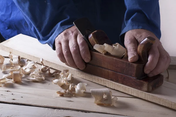 Marangoz uçak ile şantiye, ahşap arka plan üzerinde çalışıyor. Marangoz işyeri