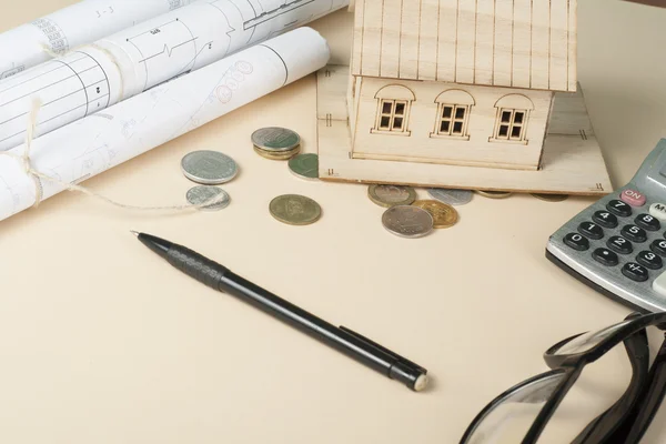 Ev tasarruf, bütçe kavramı. Model ev, not defteri, kalem, hesap makinesi ve sikkeler üzerinde ahşap ofis Resepsiyon Masası.