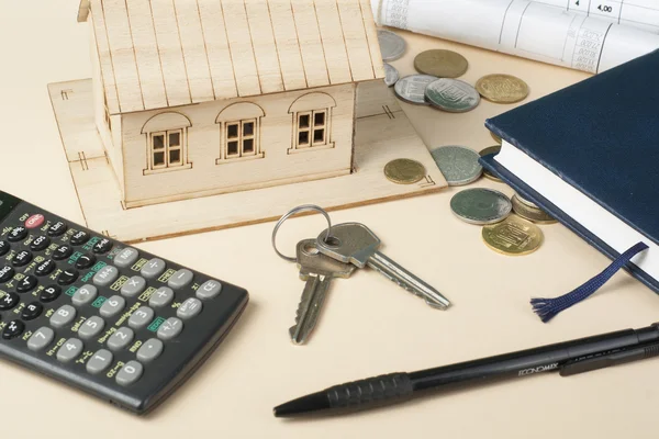 Ev tasarruf, bütçe kavramı. Model ev, not defteri, kalem, hesap makinesi ve sikkeler üzerinde ahşap ofis Resepsiyon Masası.