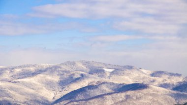 Karla kaplı tepeler ve bulutlu gökyüzü, kış kompozisyonu, düşen kar, donmuş doğa, kış zamanı arka plan