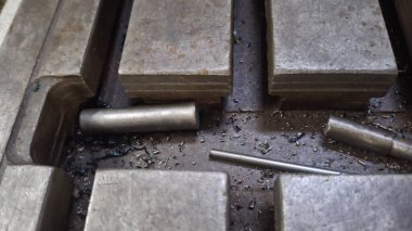 Tahta bir masanın üzerinde bir sürü metal büyüklüğünde metal boru var.,