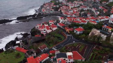 Kırmızı çatıları ve dolambaçlı yolları olan renkli uçurum kenarı köyü. Burun ve körfezin havadan temizlenmesi, teraslı bahçeler ve dar yollar. Camara de Lobos, Madeira, Portekiz