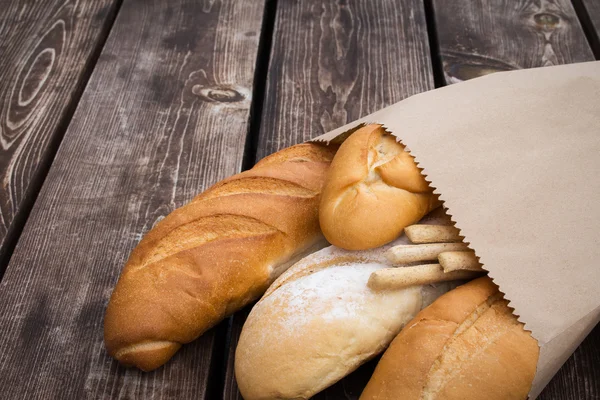 Bread in a paper bag. Loaf on a wooden table. Bakery products.