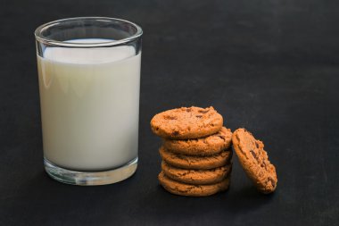 Yulaflı kurabiyeli bir bardak süt. Sağlıklı kahvaltı. Karanlık bir arka plan daki kurabiye kulesi.