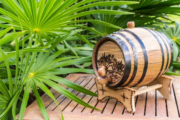Small barrel for alcoholic drinks. Wooden barrel. Mini barrel.Barrel of tequila on background of palm branches
