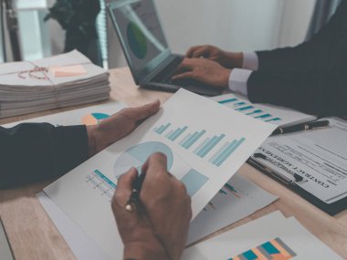 Group of business people discussing charts and graphs showing success of office meeting to analyze financial reports, planning strategies and collaboration efficiency.