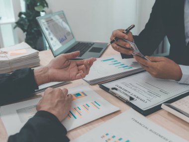 Group of business people discussing charts and graphs showing success of office meeting to analyze financial reports, planning strategies and collaboration efficiency.