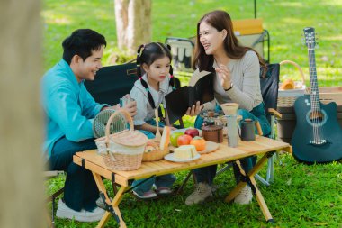 Mutlu Asyalı aile yaz tatilinde parkta piknik yapıyor. Çocuk anne ve babasıyla birlikte parkta gezinin tadını çıkarıyor. Güzel doğa..