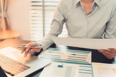 İş kadını ellerinin kalem tutuşu çalışma başarısını, mali rapor analizini, planlama stratejisini ve performansını gösteren grafikler ve grafiklerle çalışıyor. Kapat..