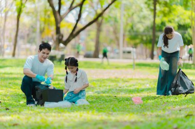 Gönüllüler parkta çöp toplar, bölgeyi temizler, gönüllü konsept, hayır kurumu, insanlar ve ekoloji, Asyalı aile plastik atık toplar, Dünya Temizlik Günü