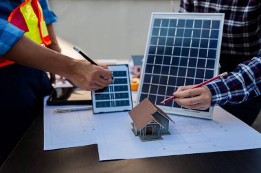 İki genç mühendis, güneş pili kurulumu uzmanı, fabrika binasında buluşup tartışıyorlar, çatıya güneş panelleri kurmayı planlıyorlar..