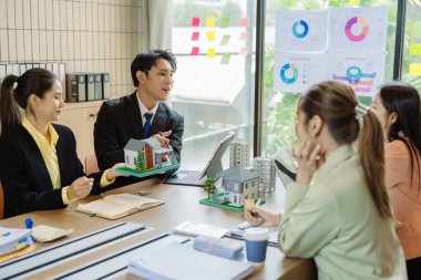 Şirket işletme ekibi potansiyel ev satışları projeleriyle tanışıyor ve karar vermeden önce onlara model evleri gösterip alıcılara teklifler sunuyor..