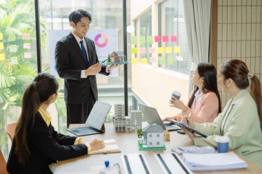 Şirket işletme ekibi potansiyel ev satışları projeleriyle tanışıyor ve karar vermeden önce onlara model evleri gösterip alıcılara teklifler sunuyor..