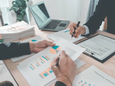 İş adamları başarılı takım çalışması, veri analizi, verimlilik ve finansal planlamanın başarısını gösteren çizelge ve grafikleri tartışıyor. Kapat..