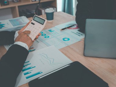 İş adamları mali raporları, planlama stratejilerini ve takım çalışması performansını analiz etme amaçlı bir ofis toplantısının başarısını gösteren çizelge ve grafikleri tartışıyor..