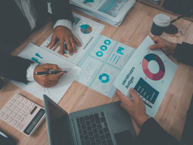 İş adamları mali raporları, planlama stratejilerini ve takım çalışması performansını analiz etme amaçlı bir ofis toplantısının başarısını gösteren çizelge ve grafikleri tartışıyor..