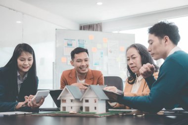 Bir grup Asyalı genç iş adamı emlak projesi için bir ofiste buluşuyorlar. Bir grup zarif, profesyonel giyimli birey küçük bir ev modelini değerlendiriyor..