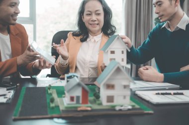 Bir grup Asyalı genç iş adamı emlak projesi için bir ofiste buluşuyorlar. Bir grup zarif, profesyonel giyimli birey küçük bir ev modelini değerlendiriyor..