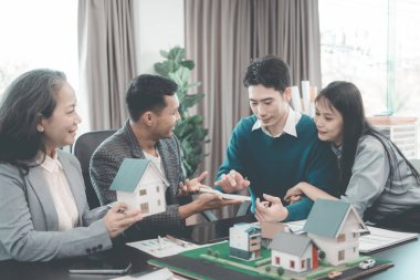 Bir grup Asyalı genç iş adamı emlak projesi için bir ofiste buluşuyorlar. Bir grup zarif, profesyonel giyimli birey küçük bir ev modelini değerlendiriyor..